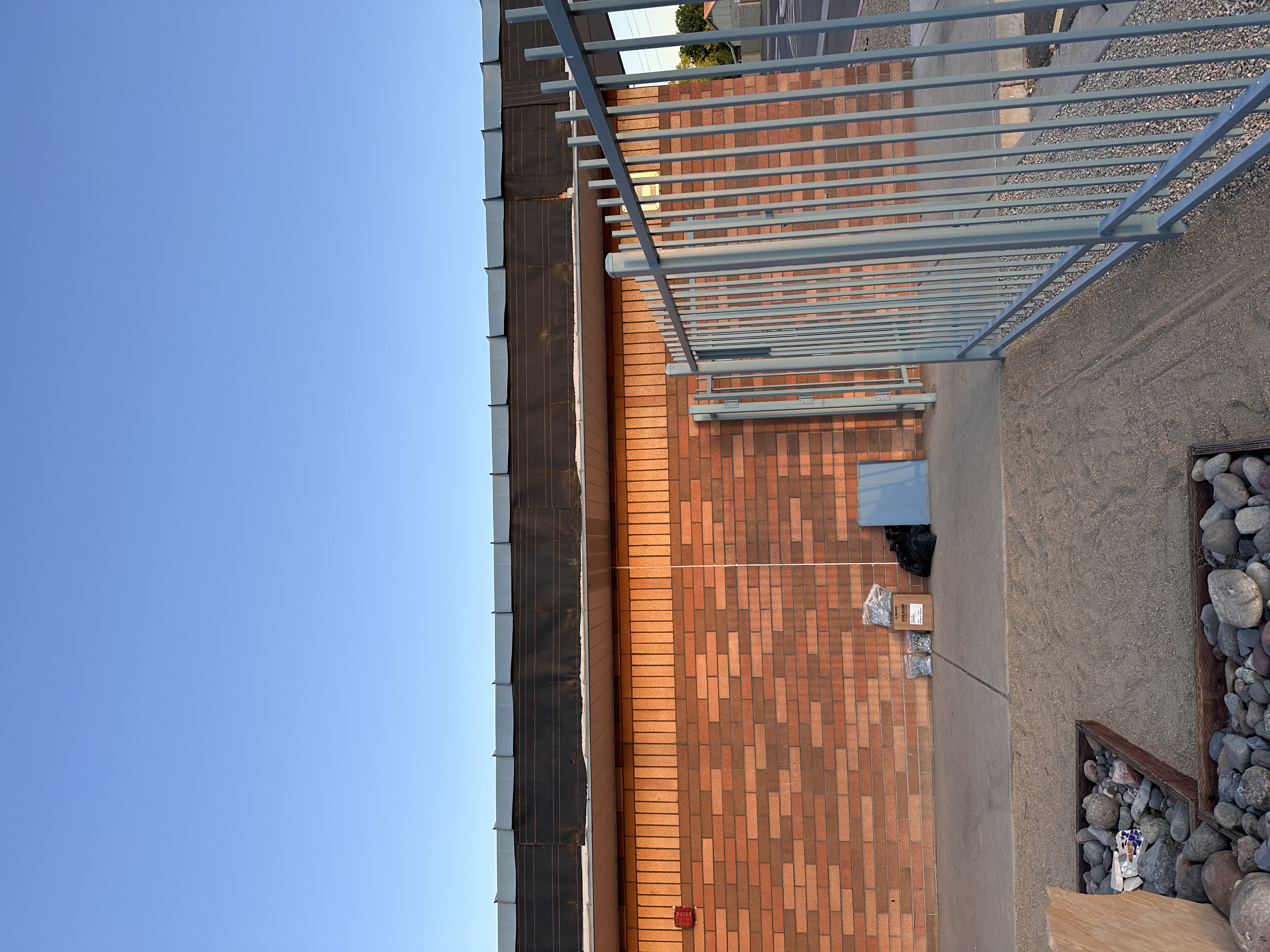 Metal patio roof installation with brick wall